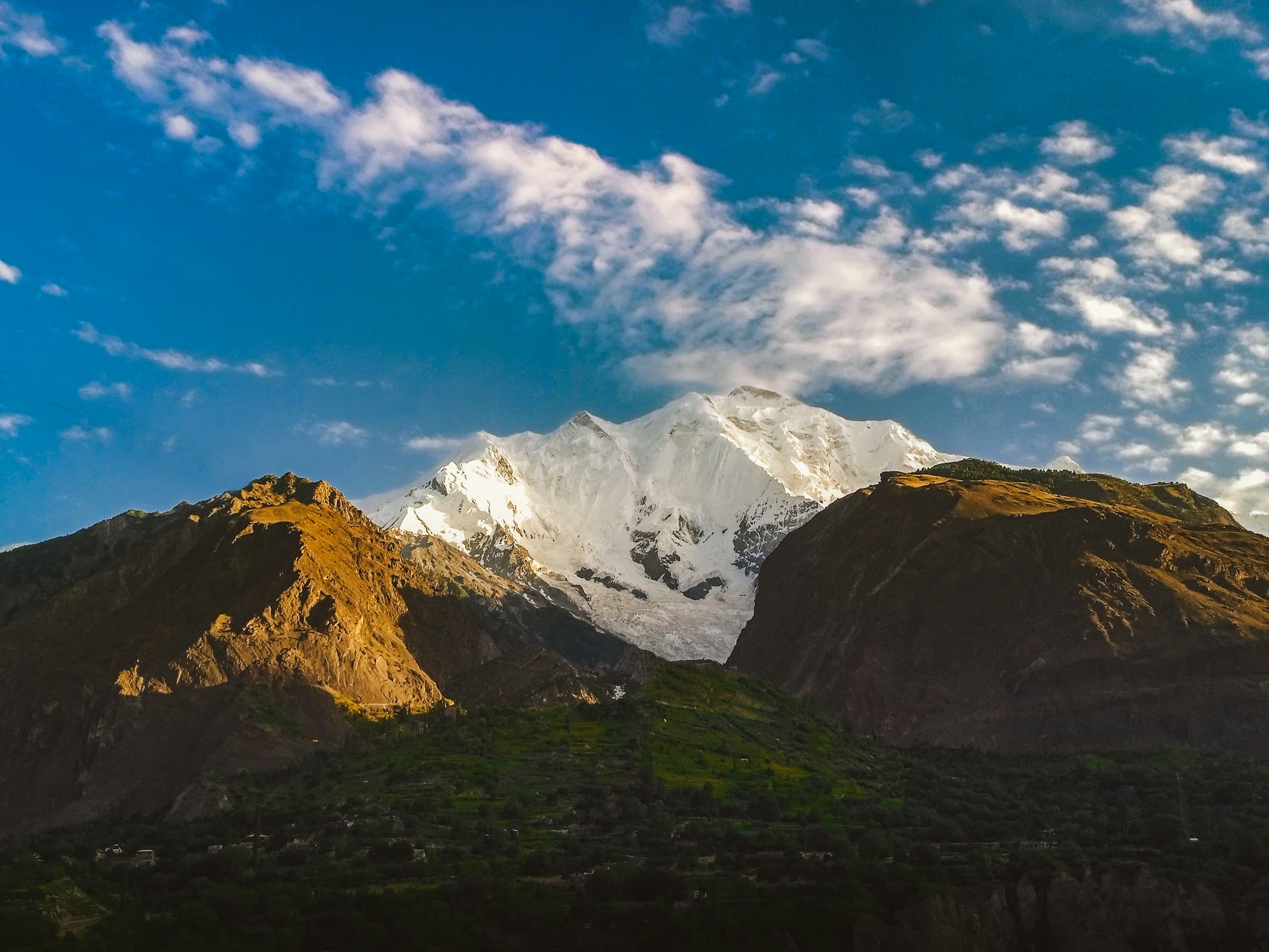 Snow-capped Karakoram peak above a terraced Hunza village at dusk